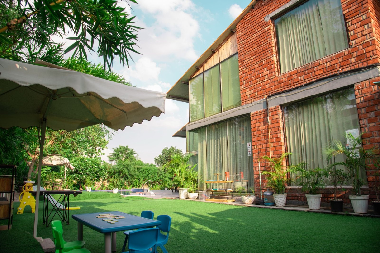 Brick villa exterior surrounded by tropical garden — We Woods Farm farmhouse Gurgaon