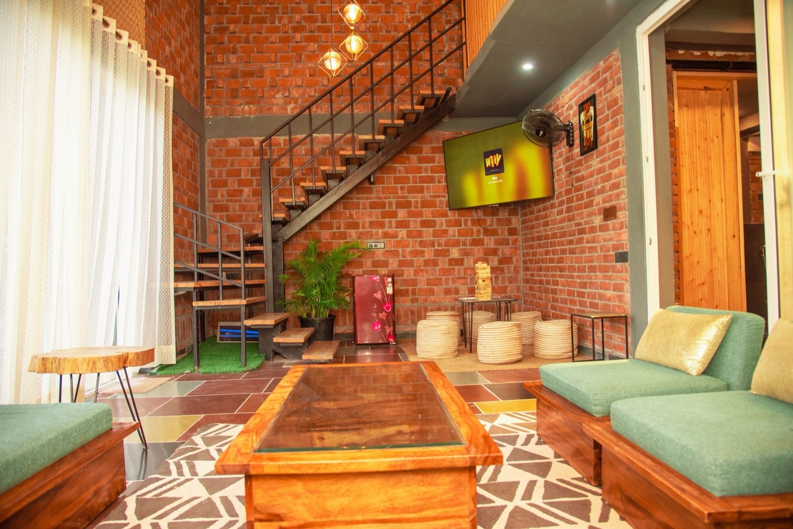 Villa lounge with industrial staircase and exposed brick — We Woods Farm Manesar Gurugram