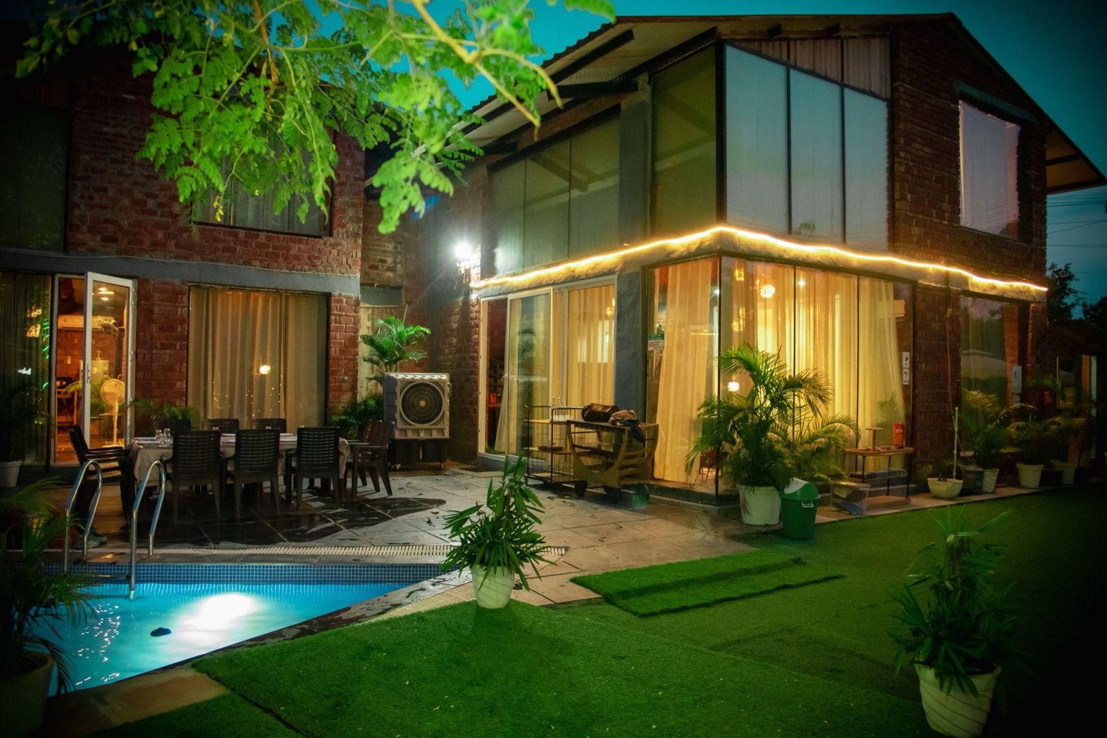 We Woods Farm farmhouse at night with pool lit up — luxury farmhouse Gurgaon Manesar